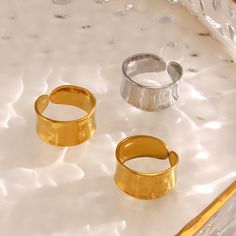 three gold and silver rings sitting on top of a white countertop next to each other