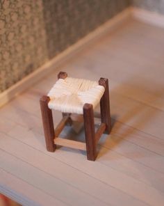 a small wooden stool sitting on top of a hard wood floor next to a wall