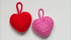 two crocheted heart shaped ornaments sitting next to each other on a white surface