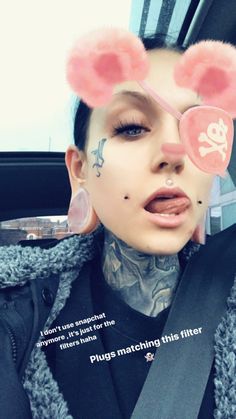 a woman with fake ears and piercings on her face, wearing a pink nose ring