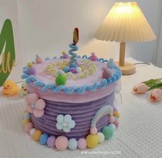 a decorated birthday cake sitting on top of a table next to a lamp and flowers