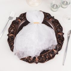 a plate with a white dress on it and silverware next to the table cloth