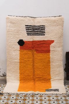 an orange and black rug on top of a white floor next to a brown chair