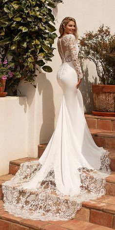 a woman in a white wedding dress standing on some steps