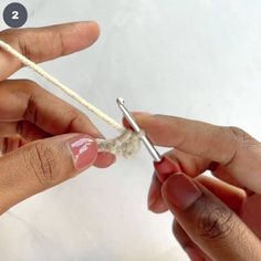 two hands are working on the end of a piece of string with scissors in each hand