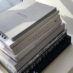 a stack of books sitting on top of a white table next to a glass window