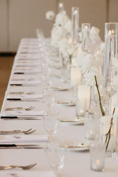 a long table is set with white flowers and candles for an elegant dinner or reception