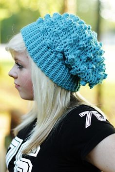 a woman with blonde hair wearing a blue crochet hat and black t - shirt