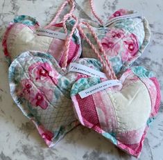 three heart shaped cushions with tags attached to them sitting on a marble counter top next to each other