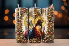 three candles with the image of jesus on them, all decorated in gold and red