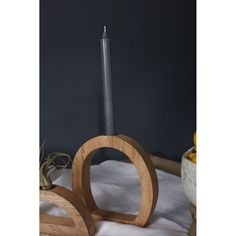 a wooden candle holder on a bed with white sheets