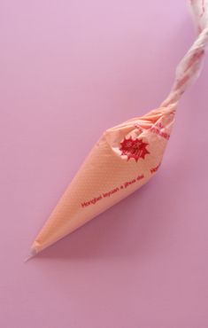 an ice cream cone with a candy cane sticking out of it on a pink background