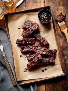 barbecue ribs and sauces on a tray next to utensils