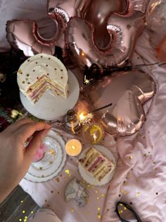 a table topped with lots of cake next to foil balloons and sparklers on top of it