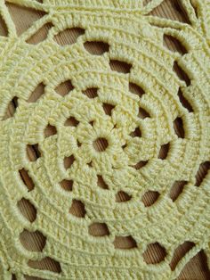 crocheted doily on wooden surface with circular design in yellow color, closeup