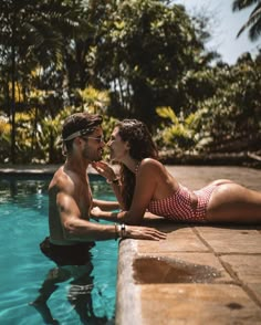 a man and woman sitting next to each other in the water near a swimming pool