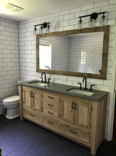 a bathroom with two sinks and a large mirror above the sink is tiled in white