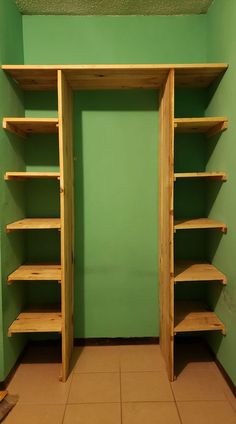 an empty closet with wooden shelves and tile flooring in front of a green wall