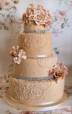 a three tiered wedding cake with flowers on the side and pearls in the middle