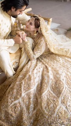 a bride and groom sitting on a bench in their wedding gowns with gold sequins