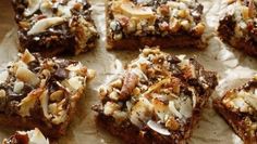 several pieces of dessert sitting on top of a piece of parchment paper covered in nuts and chocolate