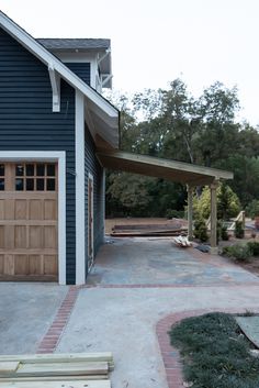 a blue house with an attached carport and wooden bench in the front yard area