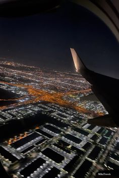 an airplane wing flying over a city at night