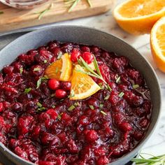 cranberry sauce in a pan with oranges and rosemary garnish on the side