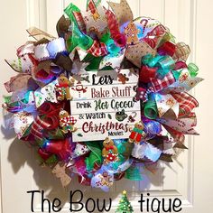 the bowtique christmas wreath is hanging on the front door, with words above it