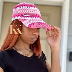 a woman wearing a pink and white crocheted hat standing in front of a door