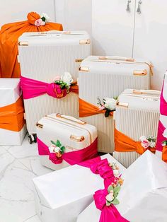 several white suitcases with pink and orange ribbons on them are sitting next to each other