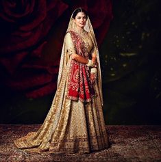 a woman in a red and gold bridal gown standing with her arms on her hips