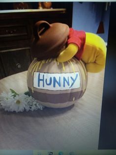 a winnie the pooh pumpkin sitting on top of a table next to a flower