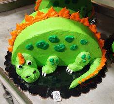 a cake shaped like a green and orange dinosaur