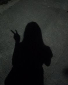 the shadow of a person holding a cell phone in their hand and pointing at something