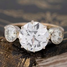 three stone diamond ring sitting on top of a piece of wood