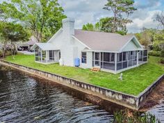 a house on the edge of a body of water with a dock in front of it