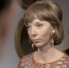 a woman in a brown dress and gold earrings