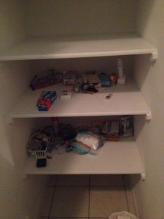 a white shelf filled with lots of items on top of a tiled floor next to a toilet