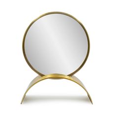 a round mirror sitting on top of a white table next to a gold metal object