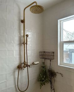 the shower head is next to the window in the bathroom with white tiles on the walls