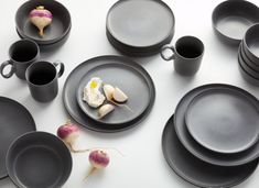 a table topped with black plates and cups