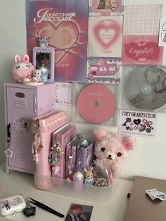 a white desk topped with lots of items and pink decor on it's wall