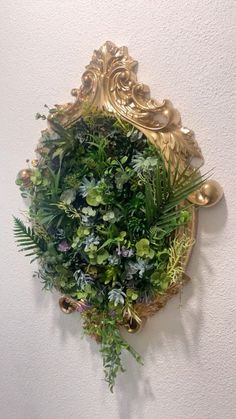 a wall mounted planter on the side of a white wall with gold trimmings