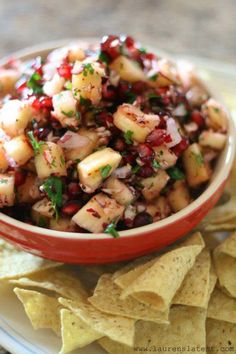 a red bowl filled with food next to tortilla chips on a white plate