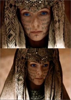 two pictures of a woman with tattoos on her face and chest, both showing blue eyes