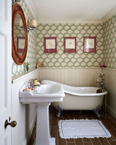 a bath tub sitting next to a white sink in a bathroom under a framed mirror