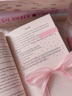 an open book with a pink ribbon on it