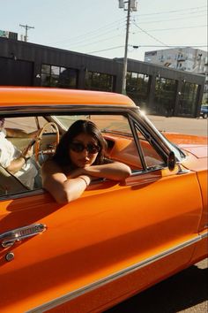 a woman sitting in the driver's seat of an orange car