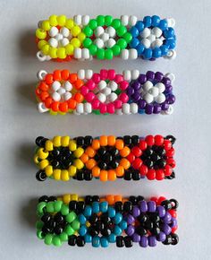 four different colors of beaded bracelets on a white surface, with one being made out of plastic beads